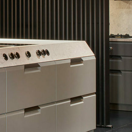 Küche mit grauem Naturstein, schräger Küchenfront und Nussbaumholz-Lamellen in der Ausstellung werkhaus bei Rosenheim